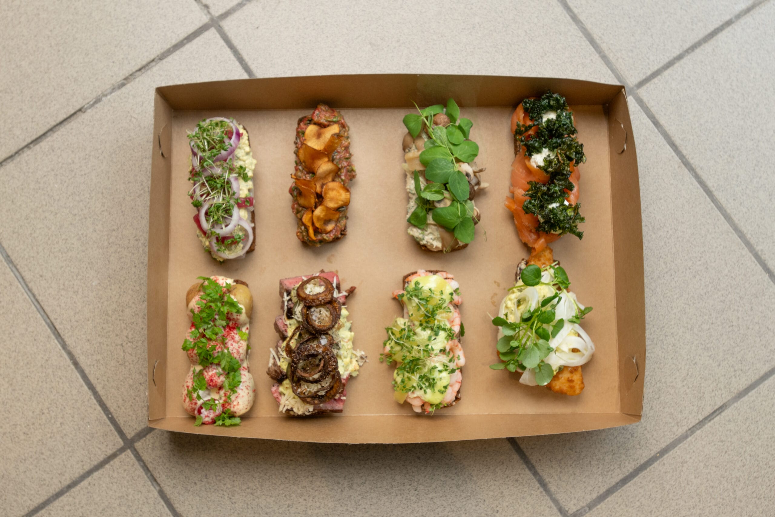 Assorterede smørrebrød i papæske set ovenfra